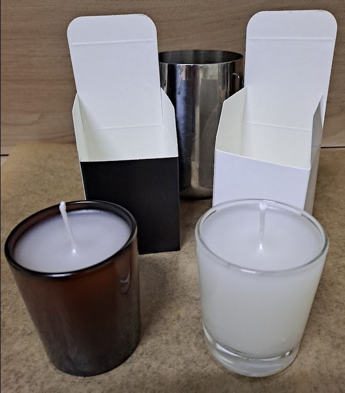 Velas de cera de abeja en vasos de vidrio ámbar y transparente con las cajas de fondo