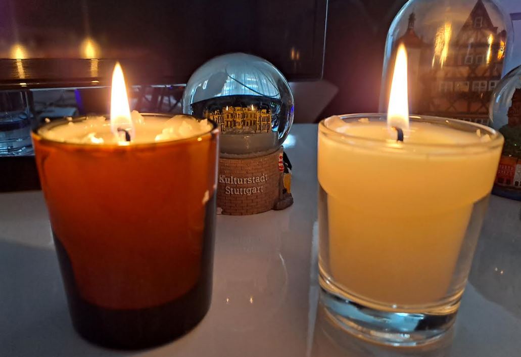Velas encendidas de cera de abeja en vidrio transparente y ámbar